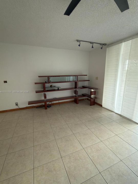 Neutral tile flooring, built-in multi-level shelving unit with wood finish, and track lighting