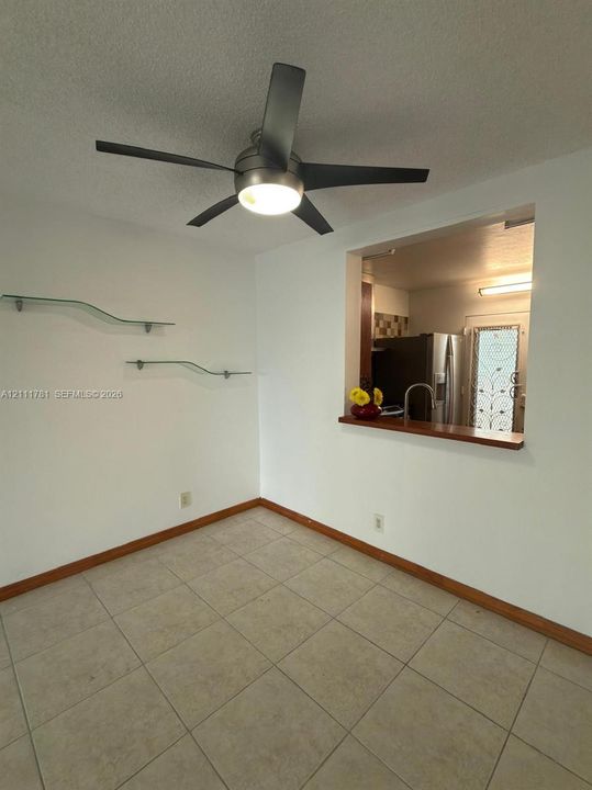 Tile flooring, five-blade ceiling fan with integrated lighting, wall-mounted glass shelving, and wood-trim service window