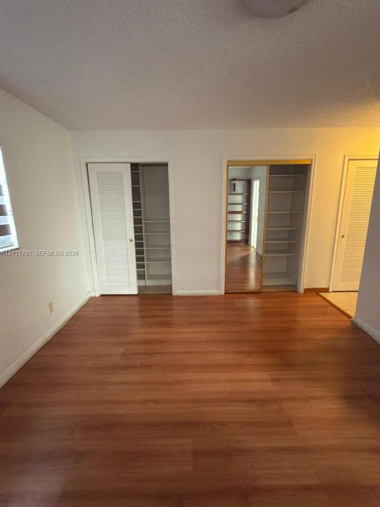 Wood-finish flooring, louvered-style closet doors, and built-in shelving units