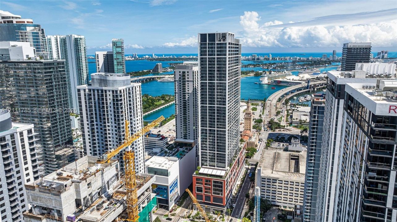 Aerial perspective of an urban high-rise landscape featuring glass-facade skyscrapers, waterfront exposure, and extensive bridge infrastructure