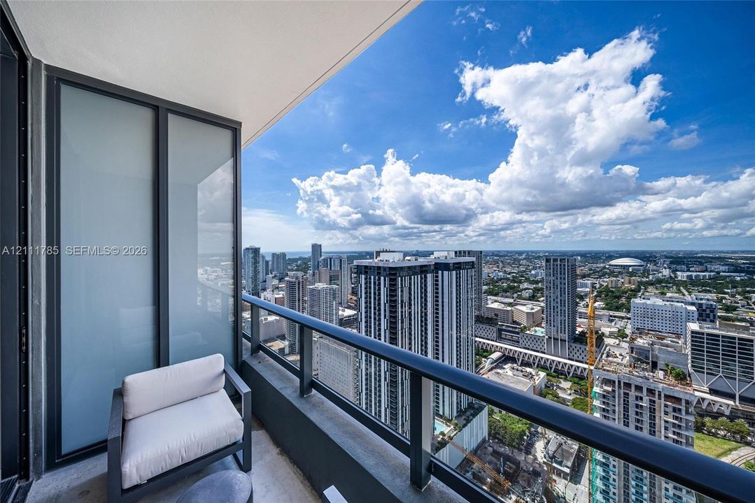 Private balcony featuring metal railings, glass paneling, and an expansive cityscape backdrop