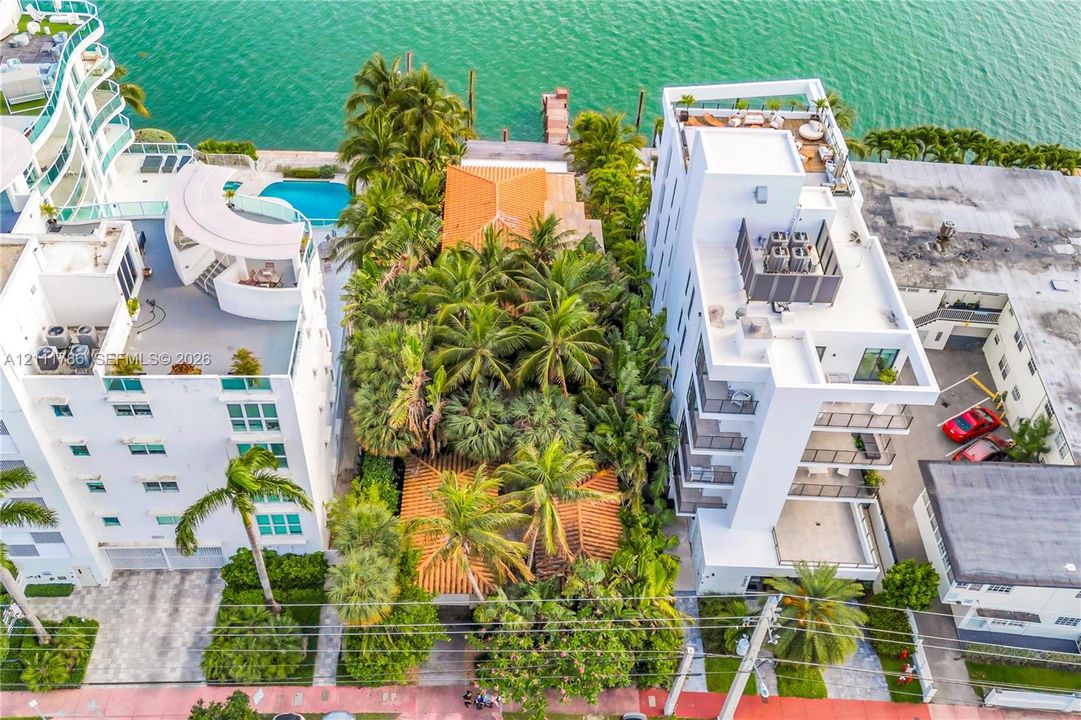 Waterfront property featuring a private dock, mature tropical landscaping, and multiple clay-tile roof structures