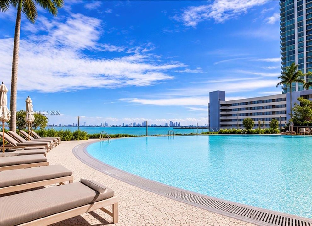 Infinity-edge swimming pool featuring a textured stone deck and coastal horizon
