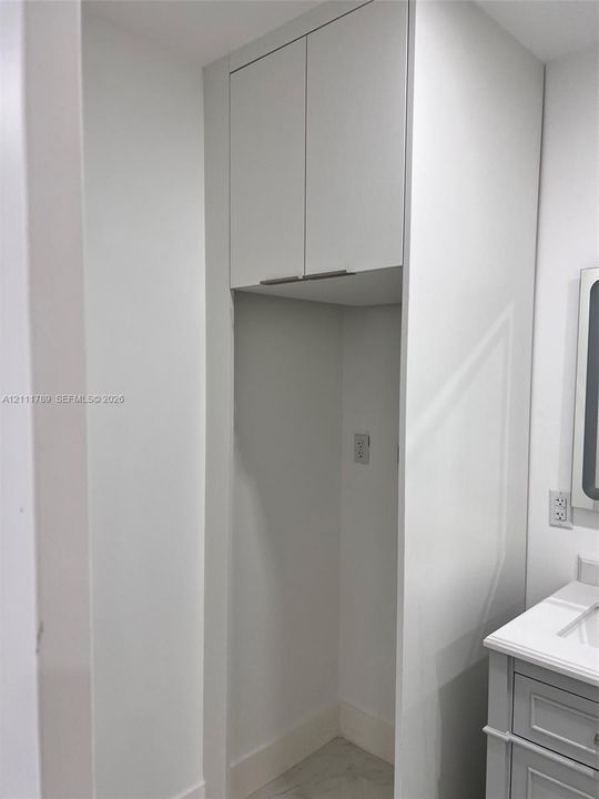 Floor-to-ceiling built-in cabinetry featuring matte white flat-panel doors and horizontal pulls, paired with a vanity offering a solid-surface countertop and integrated sink