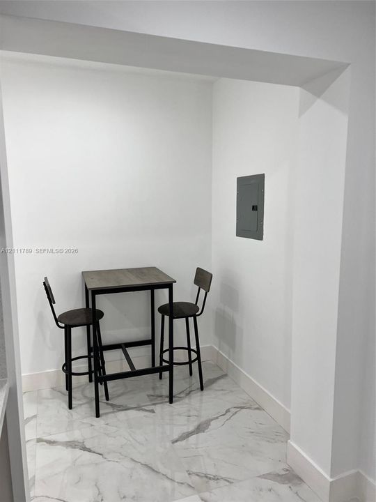 Recessed nook featuring large-format tile flooring with a veined stone-look finish and a flush-mounted electrical panel