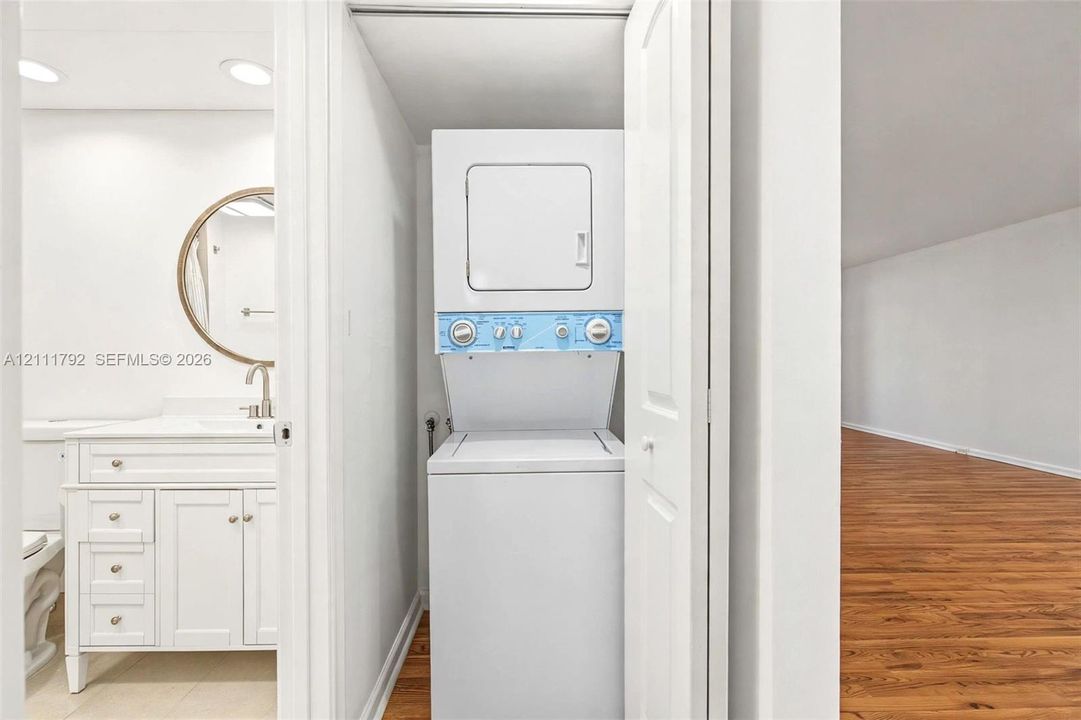 Bathroom featuring a white vanity with integrated rectangular basin and metal hardware, oval mirror with metallic trim, and a tub-shower combination with light-toned wall tile