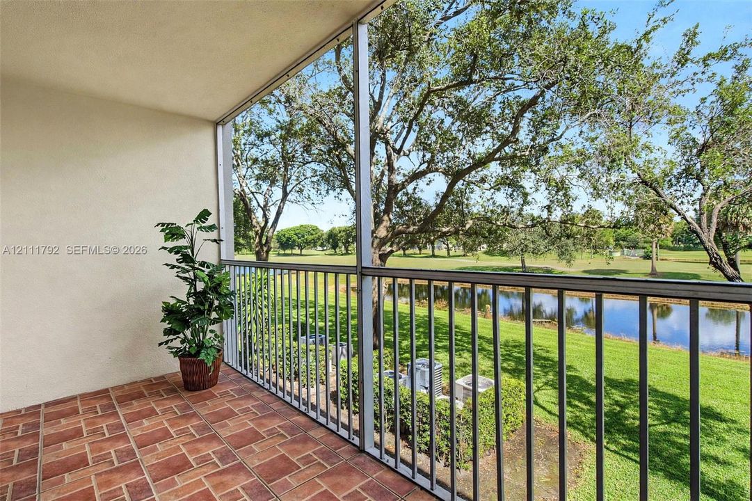 Screened-in balcony featuring terra-cotta tile flooring, metal railing, and direct water frontage