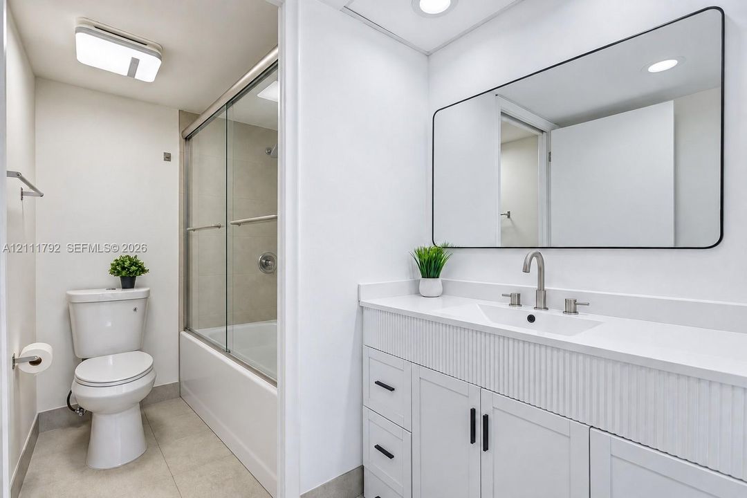 Bathroom featuring a walk-in shower with large-format neutral wall tile, pebble-stone shower floor, chrome hardware, and a white toilet