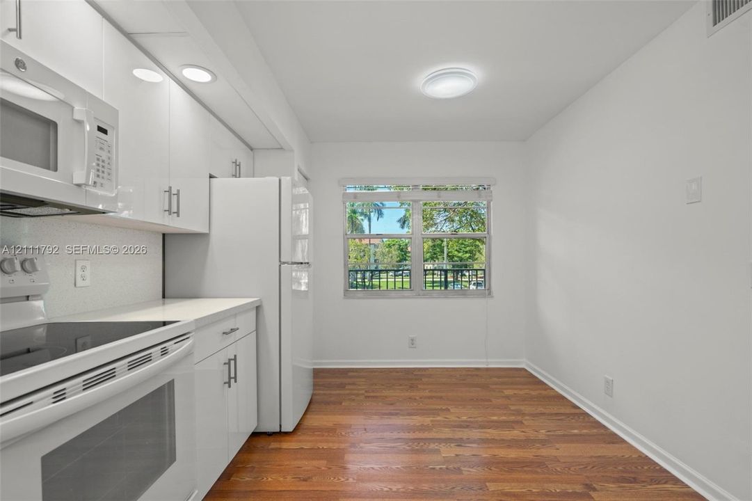 Kitchen featuring white cabinetry, solid surface countertops, a stainless steel undermount sink with a high-arch pull-down faucet, and recessed ceiling lighting
