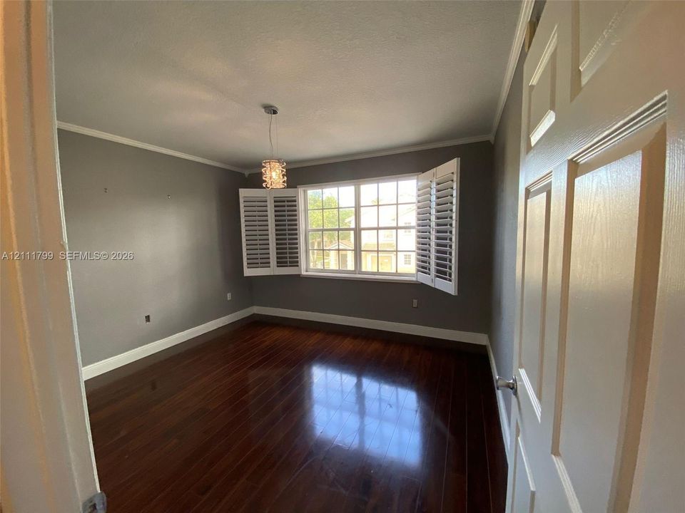Wood-finish flooring, multi-pane window with custom plantation shutters, and decorative pendant lighting
