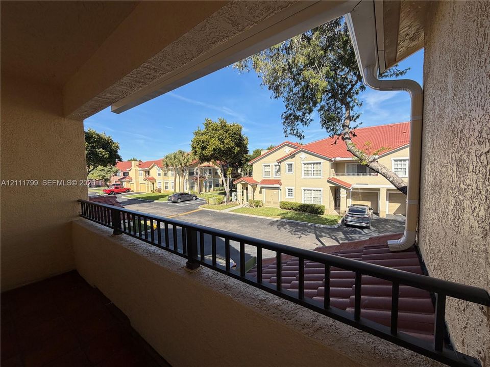 Covered balcony featuring a metal railing, textured stucco walls, and tile flooring