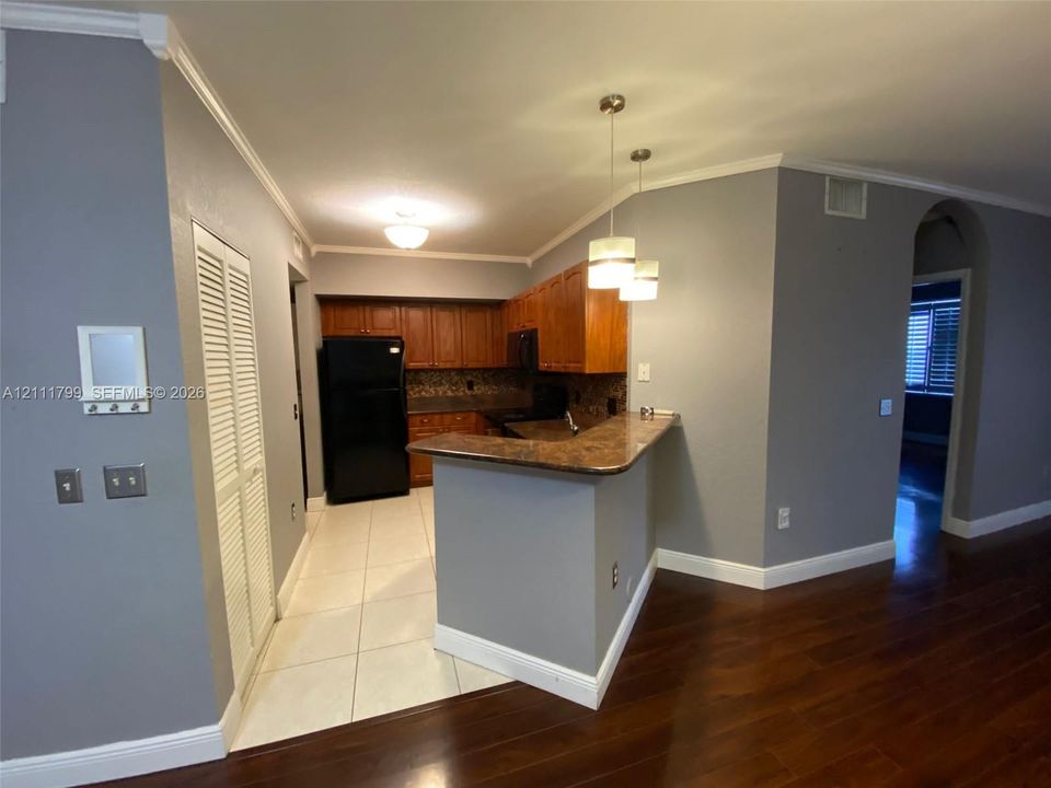 Kitchen featuring wood cabinetry, stone-finish countertops, ceramic tile flooring, and dual glass pendant lighting