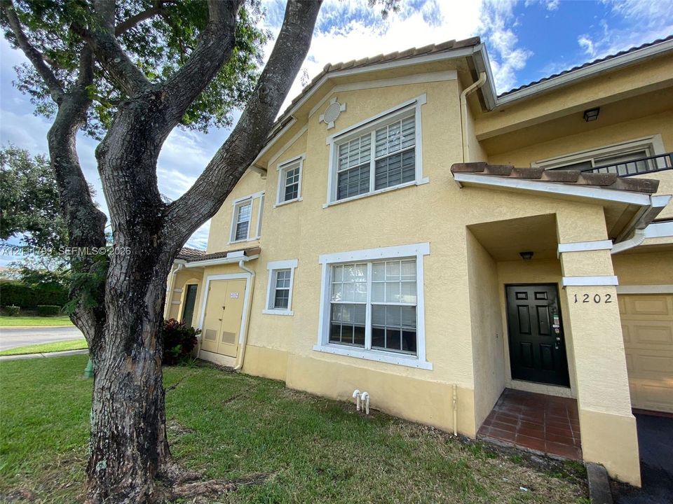 Stucco exterior featuring multi-pane windows, a tiled entryway, and an attached garage