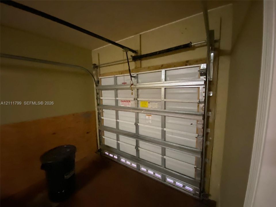 Sectional garage door with metal tracking, overhead torsion spring mechanism, and wood paneling