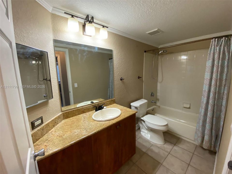 Vanity featuring a stone-look countertop, integrated oval sink with black faucet, wood-finish cabinetry, a large wall-mounted mirror, and a three-light fixture