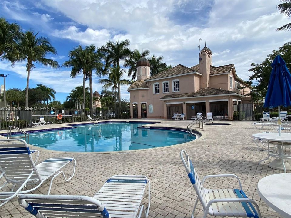 Swimming pool featuring a paver stone deck, masonry construction with cupola roof details, and mature palm landscaping