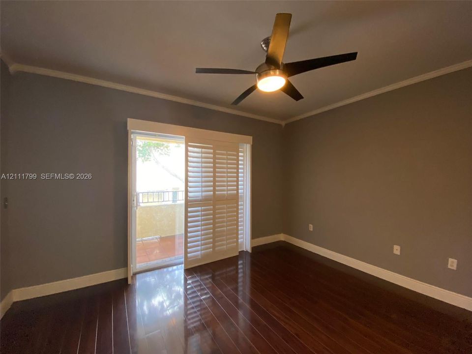 Wood-finish flooring, ceiling fan with integrated lighting, and sliding glass door with plantation shutters