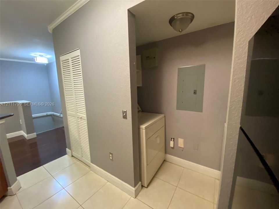 Utility space featuring large-format tile flooring, louvered closet doors, and recessed ceiling lighting