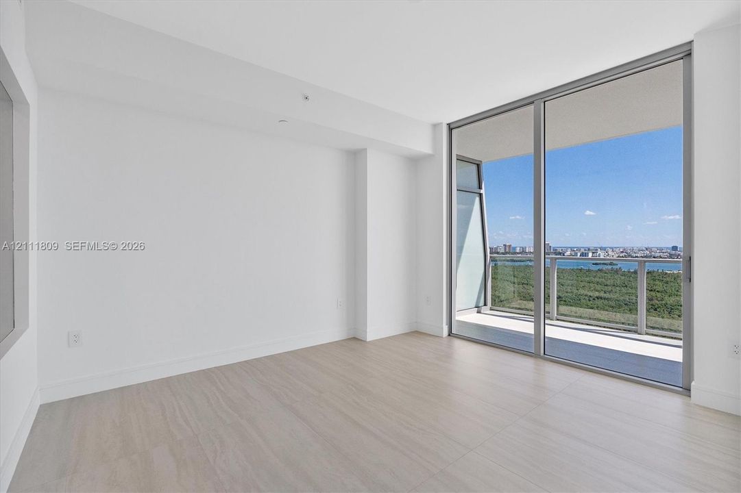 Interior space featuring light-toned tile flooring, floor-to-ceiling sliding glass doors, and a private balcony with metal railing