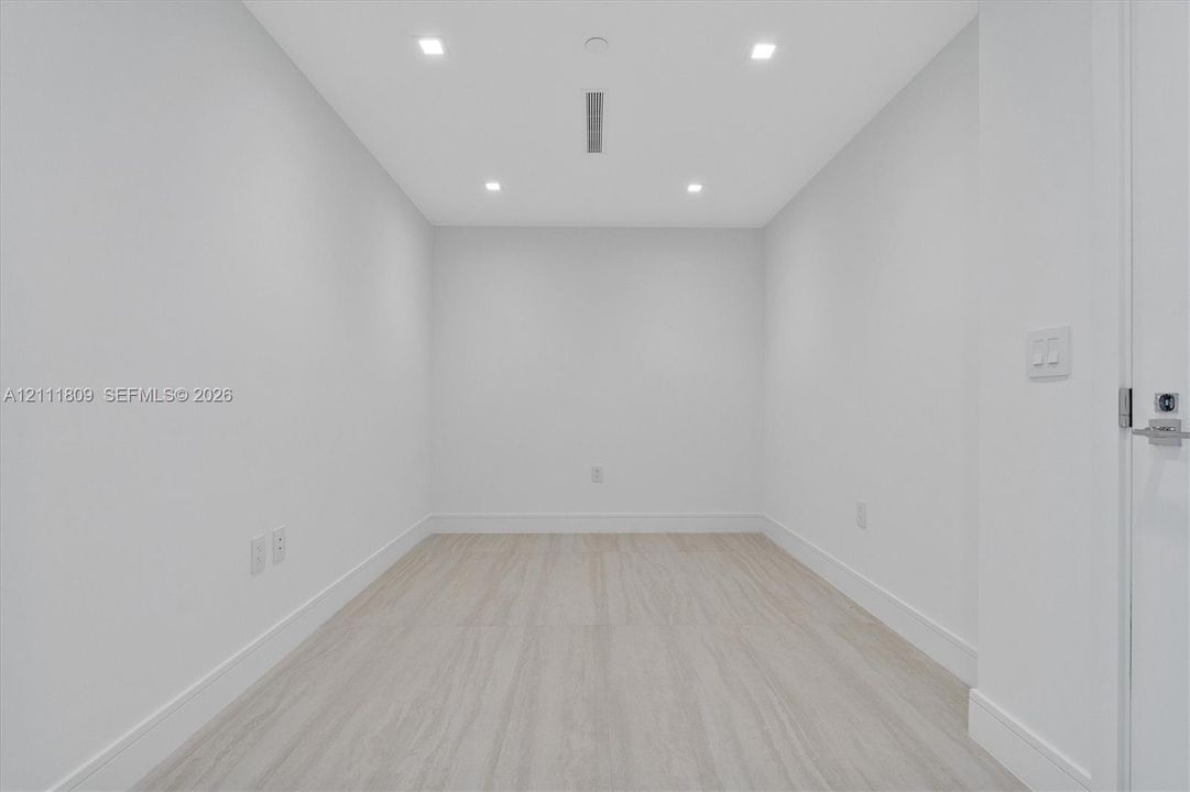 Neutral-toned interior space featuring light wood-finish flooring, recessed ceiling lighting, and crisp white walls