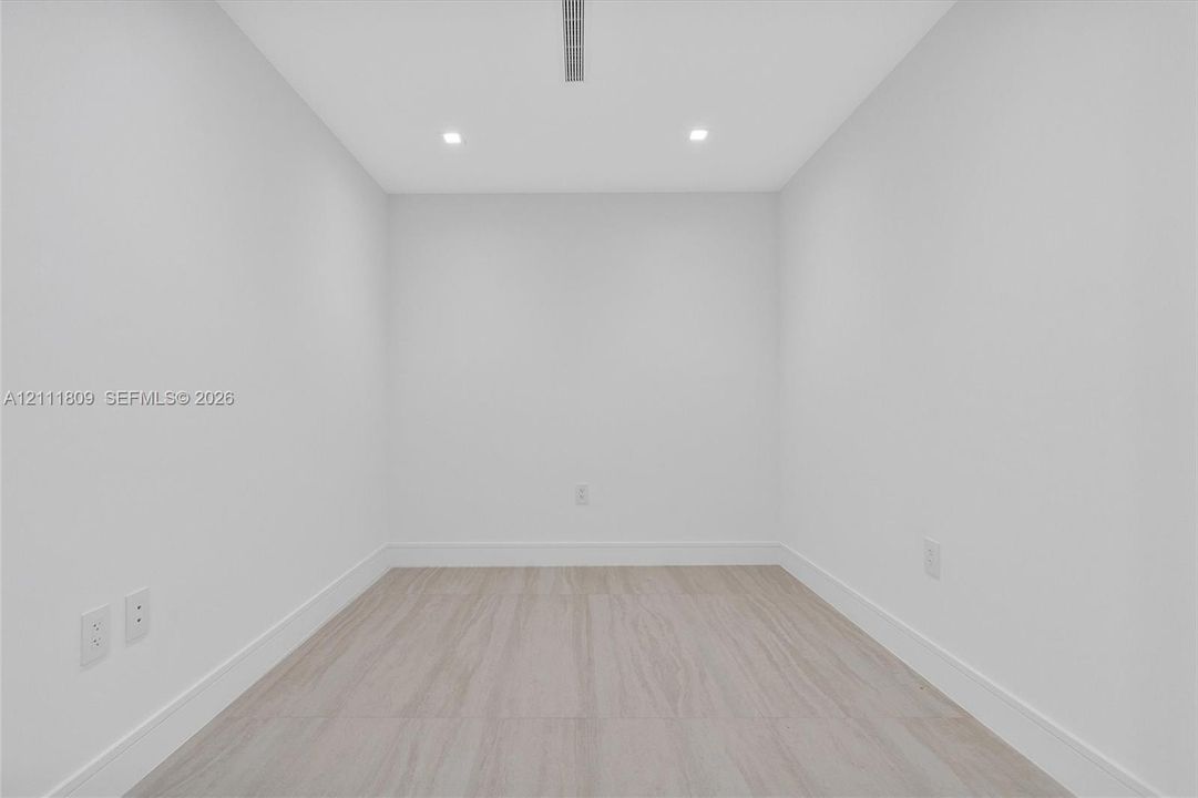 Neutral-toned wood-finish flooring, recessed lighting, and crisp white wall finishes