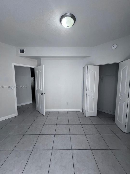 Neutral-toned ceramic tile flooring, classic paneled interior doors, and a reach-in closet featuring built-in wire shelving