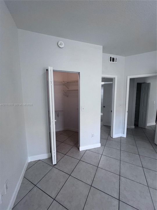 Ceramic tile flooring arranged in a diagonal pattern, interior walk-in closet featuring wire shelving, and multiple doorways with cased openings