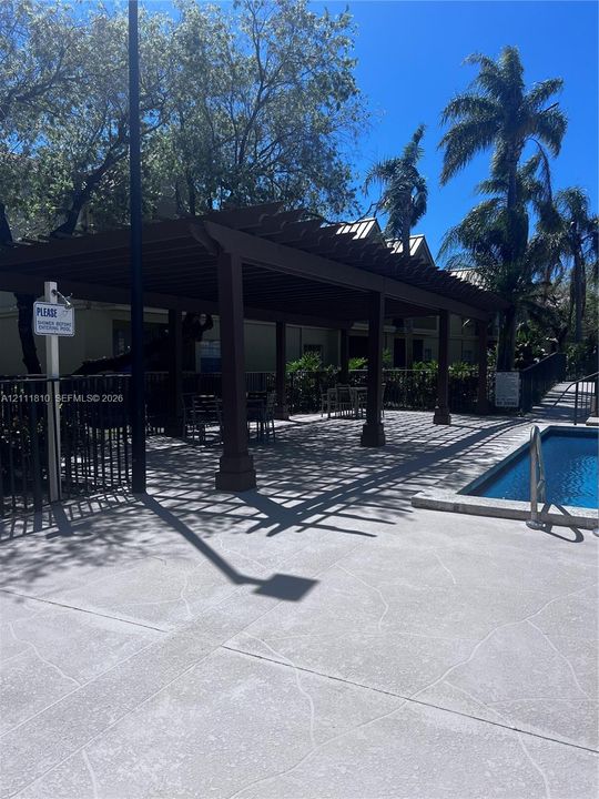 Outdoor swimming pool with a concrete pool deck and an expansive covered pergola