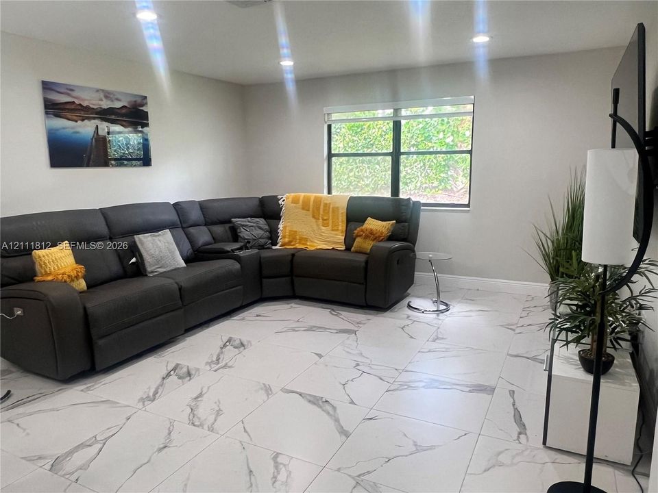 Interior space featuring white stone-finish tile flooring, recessed ceiling lighting, and a window with a neutral roller shade