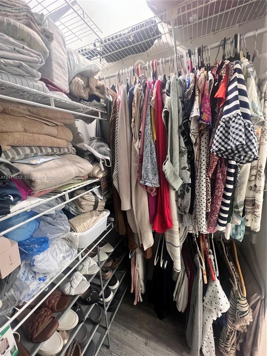 Walk-in storage space featuring tiered wire shelving, multi-level hanging rods, and integrated shoe rack organization