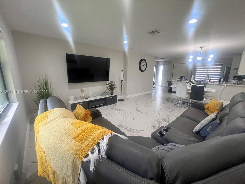 Large-format tile flooring, recessed ceiling lighting, and a modern chandelier