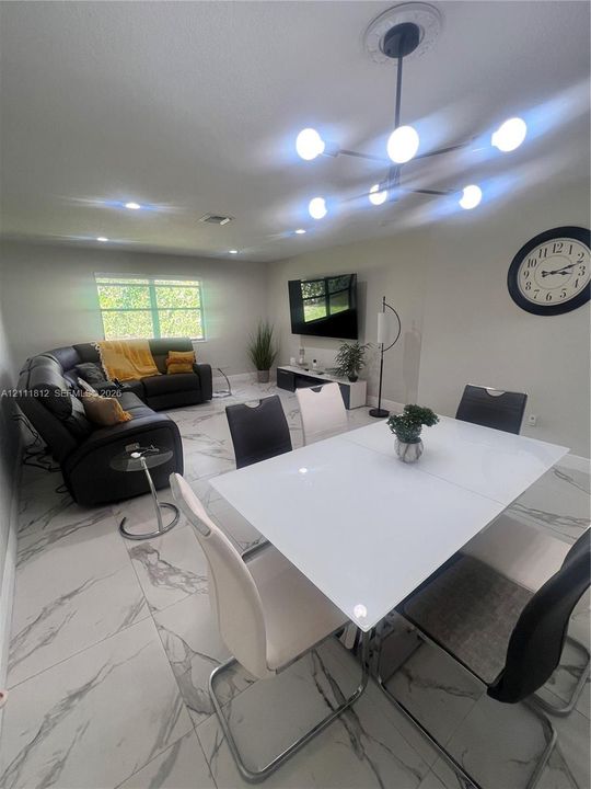 Large-format tile flooring with marble-style veining, modern multi-arm sputnik chandelier, recessed lighting, and a neutral color palette