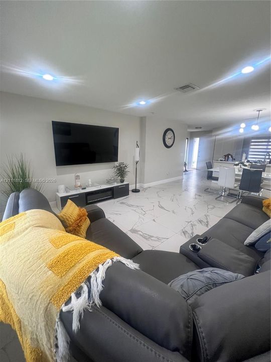 Large-format tile flooring with veined detailing, recessed lighting, and a built-in media console