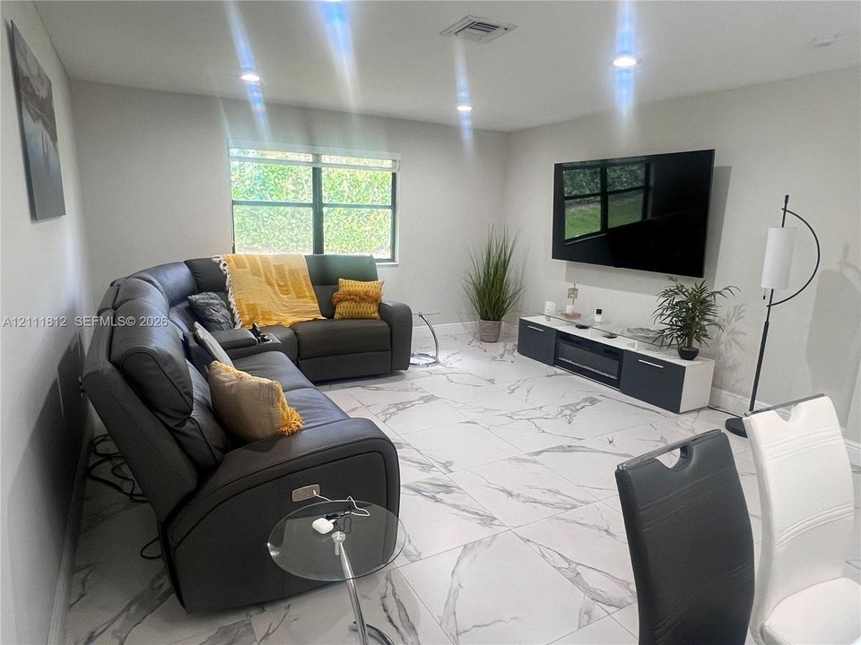 Large-format porcelain tile flooring with marble-style veining, recessed lighting, and dual-pane window