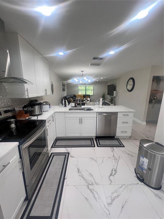 Kitchen featuring white shaker-style cabinetry, white countertops, stainless steel appliances, and large-format porcelain tile flooring