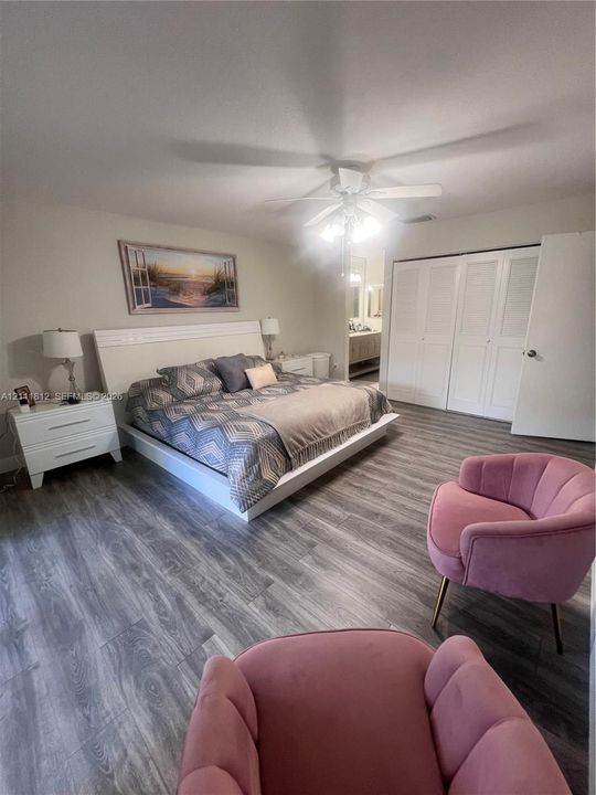 Wood-finish flooring, ceiling fan with integrated light fixture, and floor-to-ceiling louvered-style closet doors