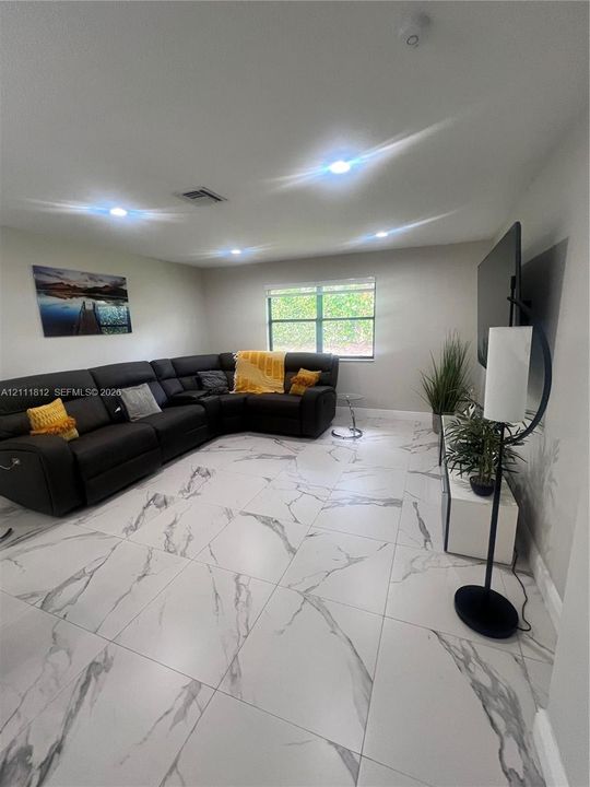 Large-format tile flooring with veined detailing, recessed ceiling lighting, and a dual-pane window