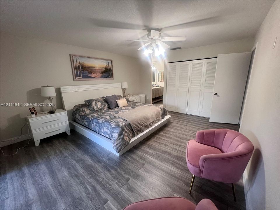 Wood-finish flooring, ceiling fan with integrated lighting, and louvered double-door closet