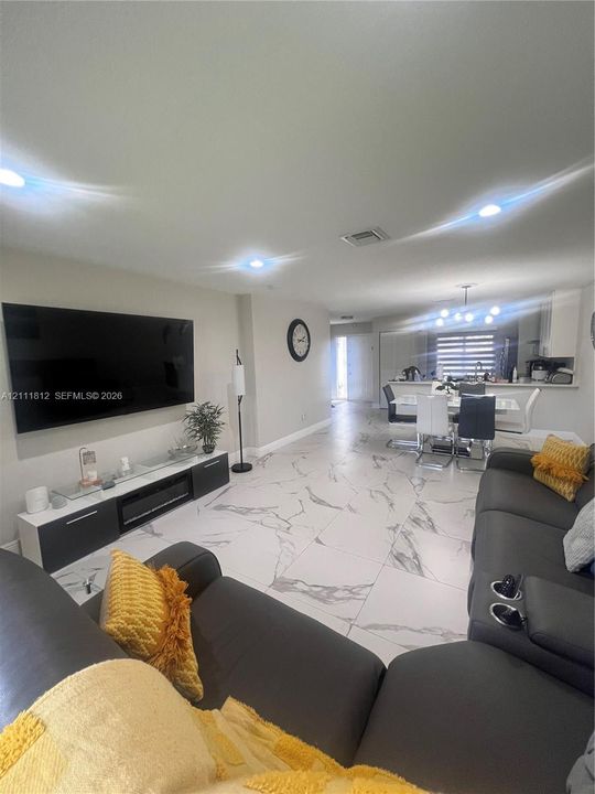 Open-concept living space featuring large-format tile flooring with a stone-finish pattern and recessed ceiling lighting