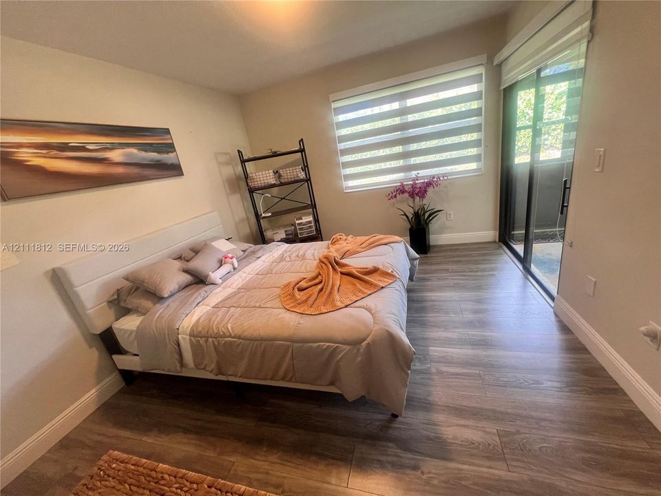 Neutral wall tones, wood-finish flooring, dual-layered window shades, and sliding glass patio door