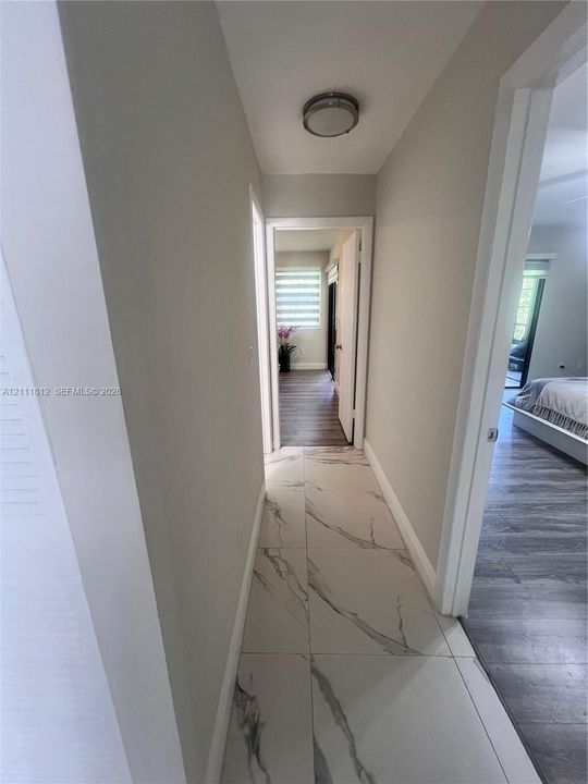 Large-format stone-style tile flooring with veining detail, recessed flush-mount lighting, and wood-finish flooring