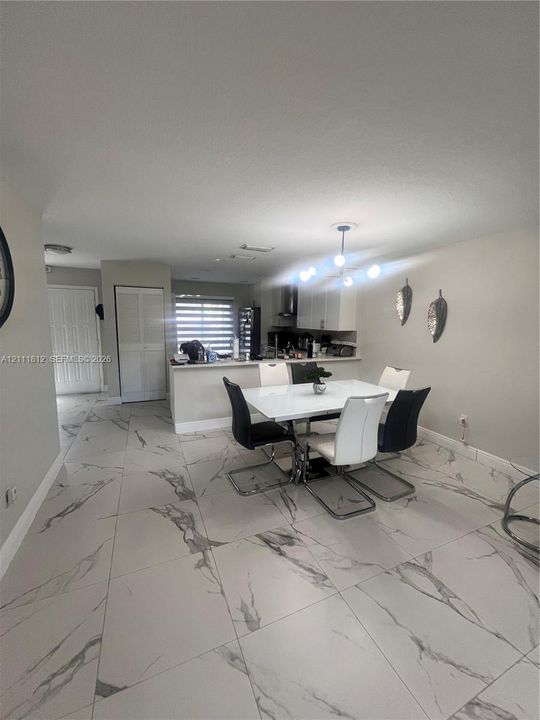 Large-format, veined tile flooring, peninsula kitchen counter, multi-globe light fixture, and louvered-door closet