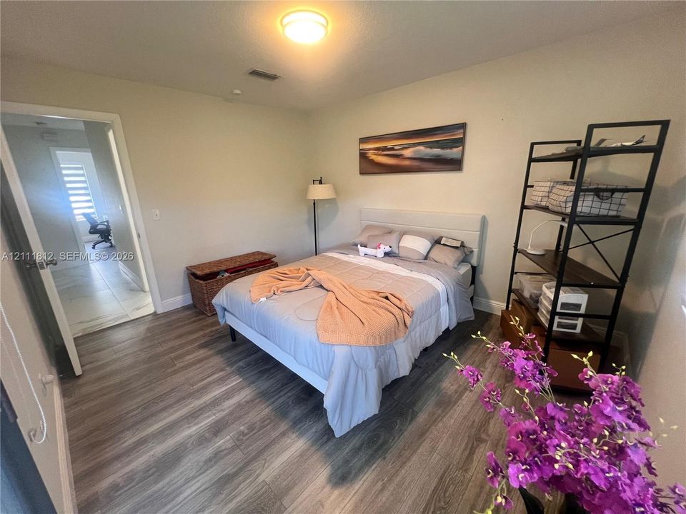 Neutral wall finishes, wood-finish flooring, and a flush-mount overhead light fixture