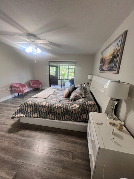 Wood-finish flooring, ceiling fan with integrated lighting, and glass-paned exterior door leading to a screened enclosure