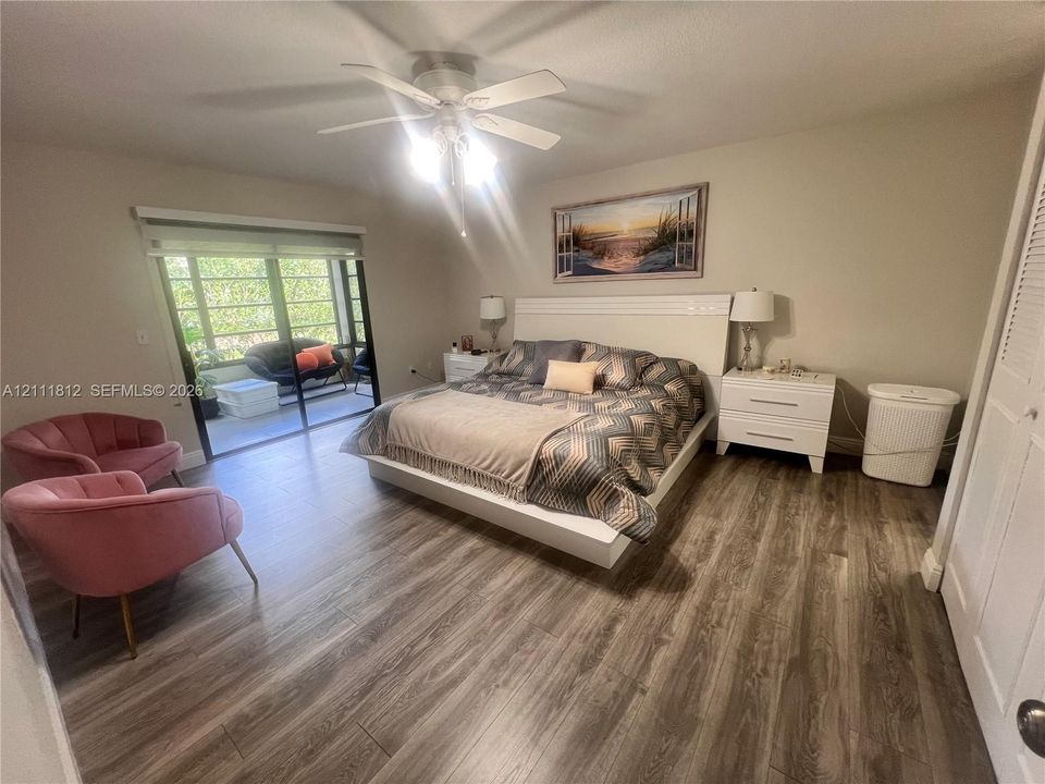Wood-finish flooring, ceiling fan with integrated lighting, and sliding glass doors leading to a screened enclosure