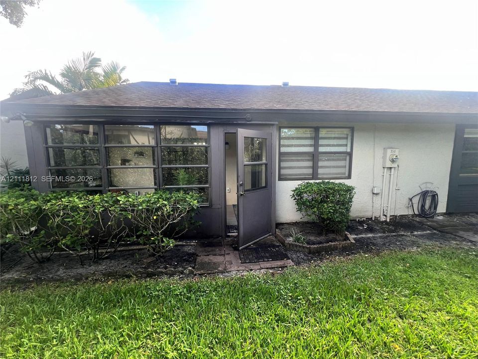 Exterior view featuring a low-slope roof, multi-pane window configuration, framed glass-panel entry door, and light-toned textured wall finish