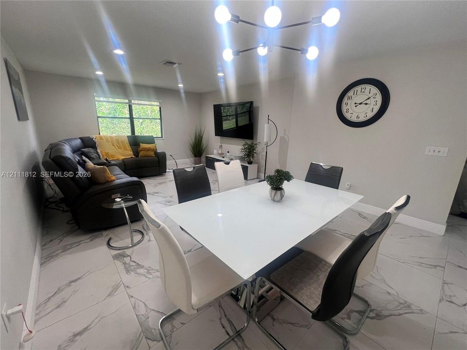 Large-format tile flooring with veined detailing, modern multi-arm chandelier, and recessed lighting