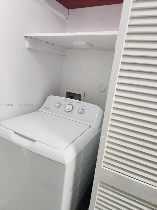 Laundry area featuring a built-in overhead storage shelf and louvered closet doors