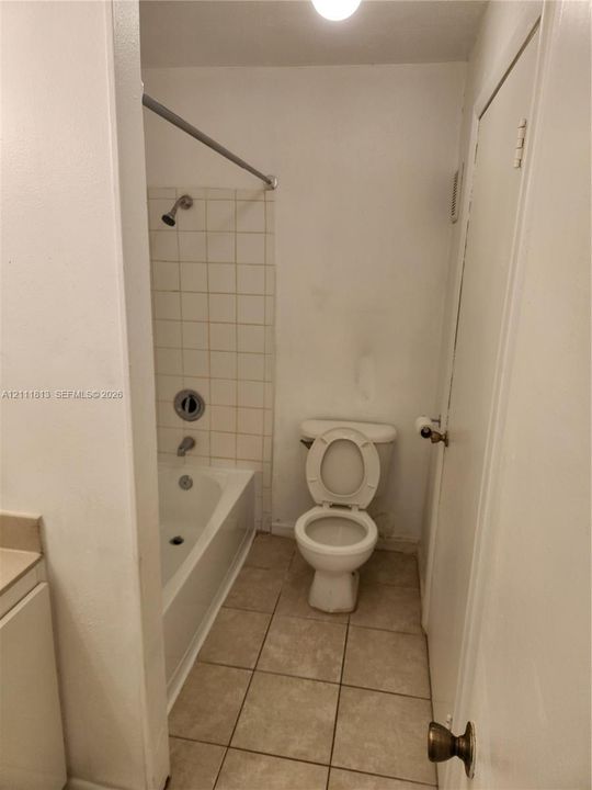 Bathroom featuring ceramic tile flooring, a tub-shower combination with white wall tile, and a porcelain toilet