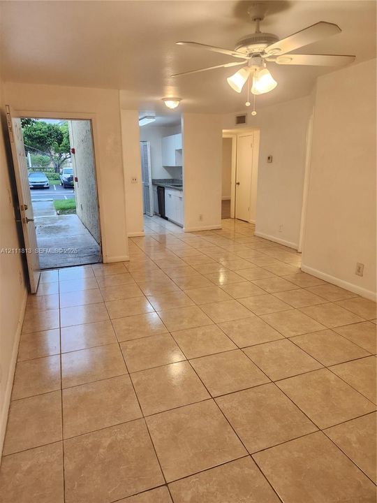 Neutral ceramic tile flooring, ceiling fan with integrated lighting, and white cabinetry